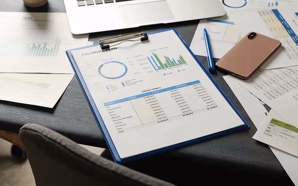 Documento di pianificazione finanziaria con grafici, laptop e smartphone su una scrivania